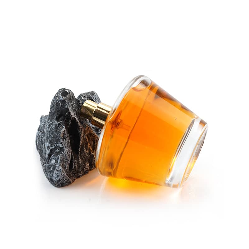 Cosource cone shaped glass perfume bottle with amber liquid and black textured cap on white background