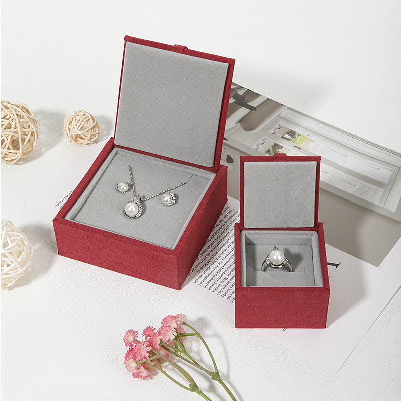 Luxury ribbon pull jewelry box with flip-top design, opened to display velvet interior

